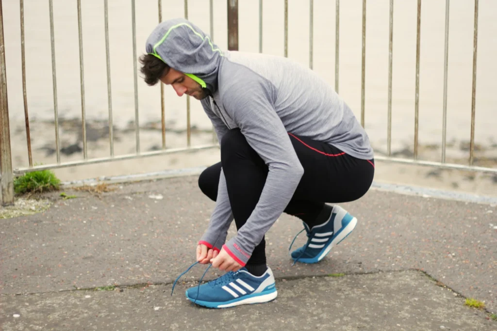 Athletic person tying shoes demonstrating obedience to fitness goals and mastering habits through consistency